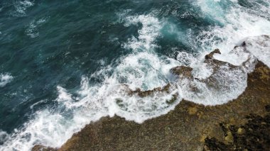 Sahilde deniz dalgaları ve köpüklerin yakın plan çekimi.