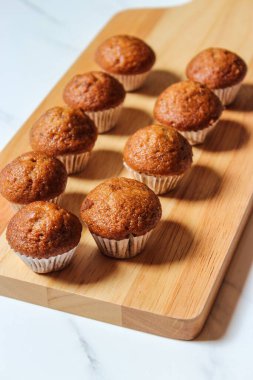 Ev yapımı lezzetli kahverengi keklerle ahşap bir tahtanın dikey yakın çekimi.