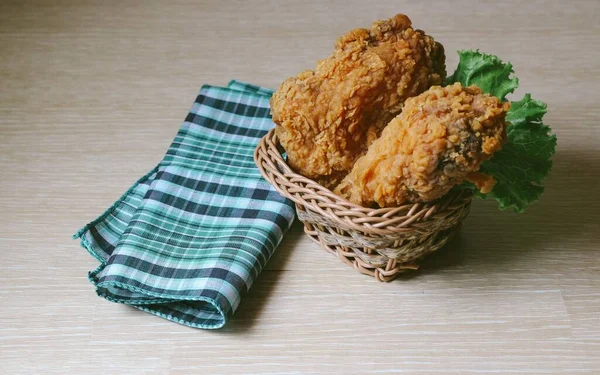 一个脆炸鸡和一个木制桌子上的格子厨房毛巾 — 图库照片