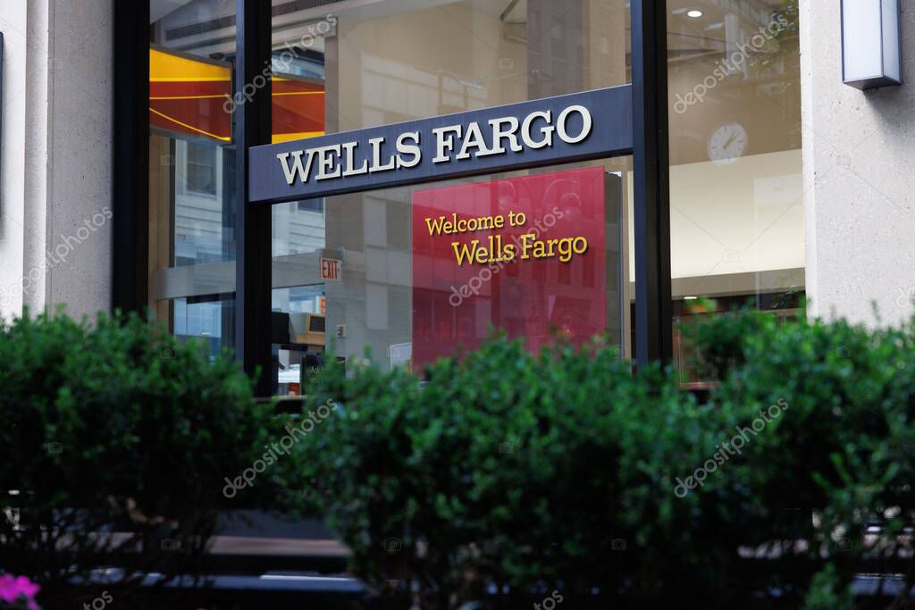 Wells Fargo branch front with prominent logo in New York. Classic Wells Fargo logo on background of green bushes