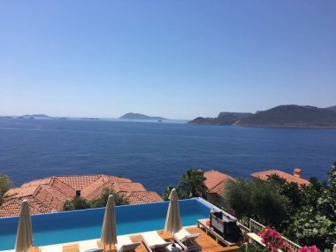 Güzel bir deniz manzarası ve yüzme havuzlu bir otelden tepeler.