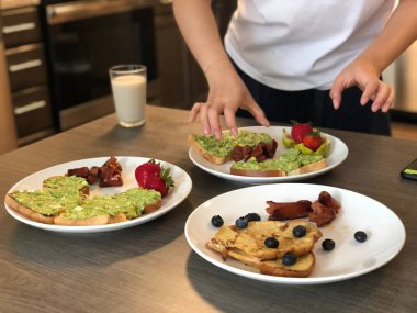 Kafedeki ahşap bir masada lezzetli tatlılar hazırlayan bir kadının yakın çekimi.