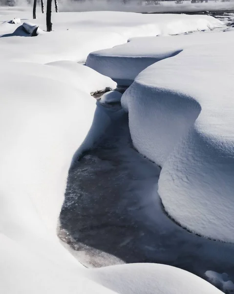 冬の牧草地で凍った狭い川の抽象的な雪のショット — ストック写真