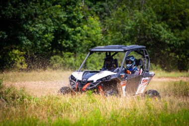 Toprak yolda yan yana giden bir araçta (UTV) sürücülere yakın çekim