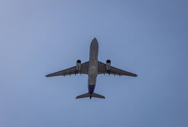 A passenger airplane flying overhead in the blue sky