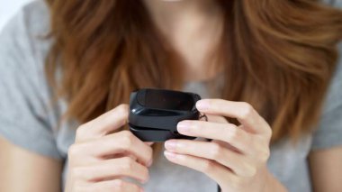 Kan oksijenini ölçmek için siyah nabız oksimetresindeki bir kadının parmağına yakın çekim.