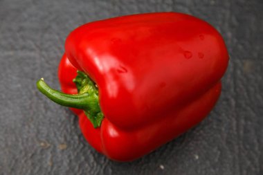 Koyu ahşap bir yüzey üzerinde taze kırmızı biber (çan biberi) yakın plan çekimi.