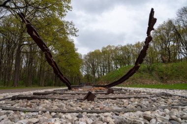 Yeşil ağaçlar arasında beyaz taşlar olan paslı bir demiryolu.