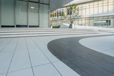 Modern ofis binasının önündeki beyaz ve gri zemin katın üst görüntüsü.