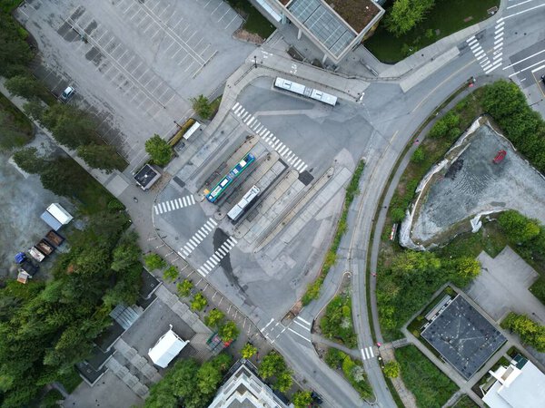 A high-angle shot of a confusing urban street with buildings a parking lot and trash bins
