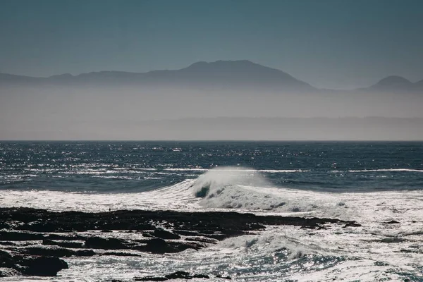Красивий Морський Пейзаж Розбитими Хвилями Туманним Гірським Силуетом Задньому Плані — стокове фото