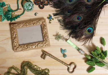 Tahta bir masanın üzerinde anahtar ve tavus kuşu tüyü olan altın bir çerçevenin üst görüntüsü.