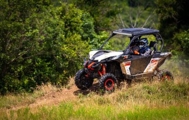 Toprak yolda yan yana giden bir araçta (UTV) sürücülere yakın çekim