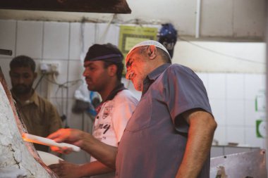 Erkekler Bahreyn şehrinde geleneksel fırında ekmek pişiriyorlar.