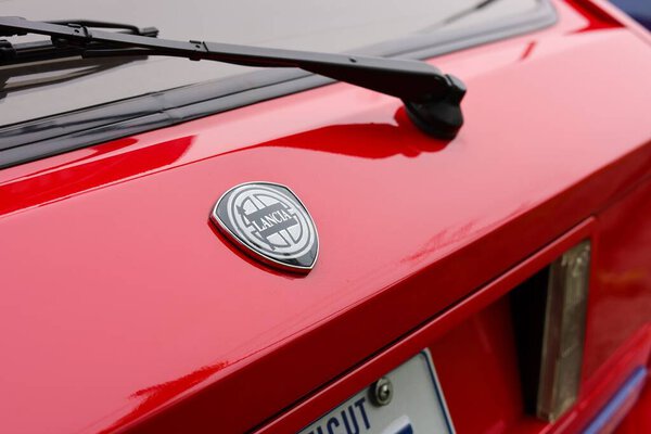 A close-up of a black and white Lancia badge on a red car