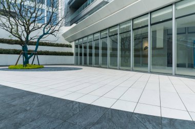 Modern ofis binasının önündeki beyaz ve gri zemin katın üst görüntüsü.