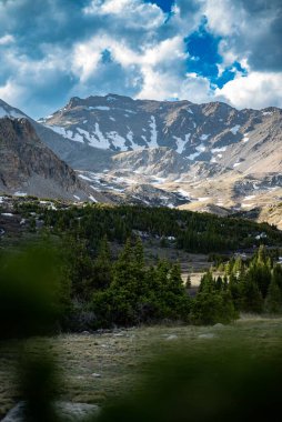 Gökyüzünde bulutlar olan güzel bir dağ manzarasının dikey görüntüsü.