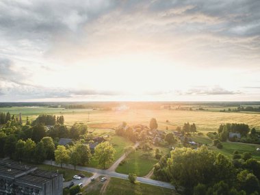 Doğadaki bir köyün gündoğumunda ekilmiş tarım arazisiyle yüksek açılı görüntüsü.