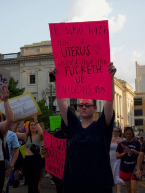 Arka planda diğer protestocularla birlikte New Orleans 'ta kürtaj haklarıyla ilgili hoşnutsuzluğunun bir işareti olan bir kadının dikey çekimi.
