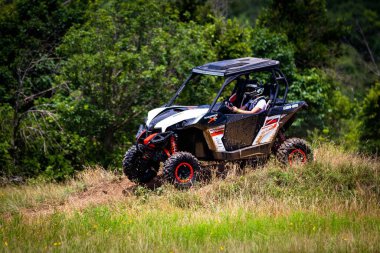 Toprak yolda yan yana giden bir araçta (UTV) bir sürücünün yakın çekimi