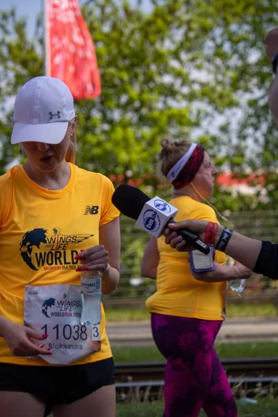 A reporter with microphone interviewing a runner at Wings for Life World Run