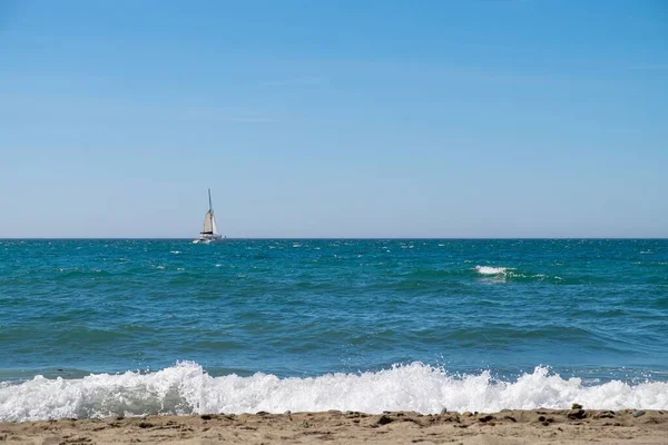 海岸近くの海を航行するセーリング カタマランまたは複数の船体の帆船のビーチからの眺め — ストック写真