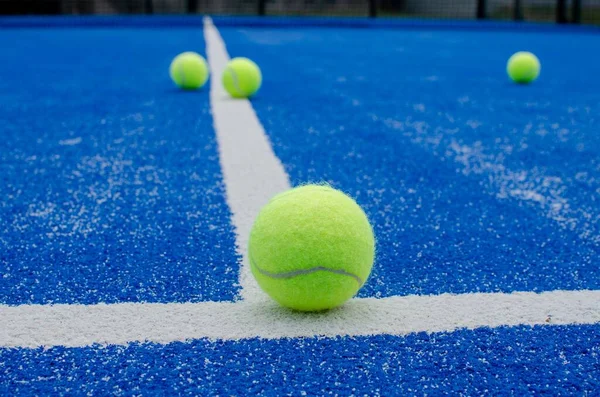 selective focus, several paddle tennis balls on a blue artificial grass paddle tennis court