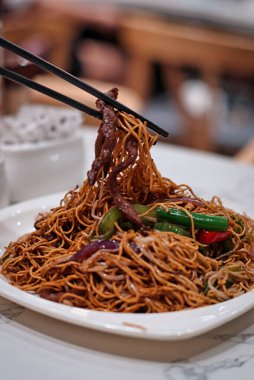 Lokantada erişte ve sığır eti tutan çubukların dikey yakın çekimi.