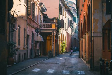 Güneşli bir günde İtalya 'nın Bologna şehrinde renkli binaları olan küçük bir yoldan geçen biri.