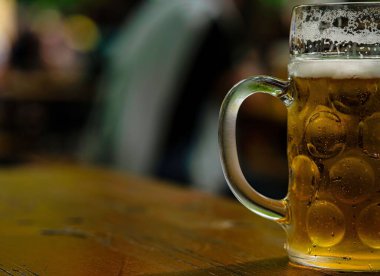 Bulanık bir yerde bir bardak soğuk biranın yakın çekimi.