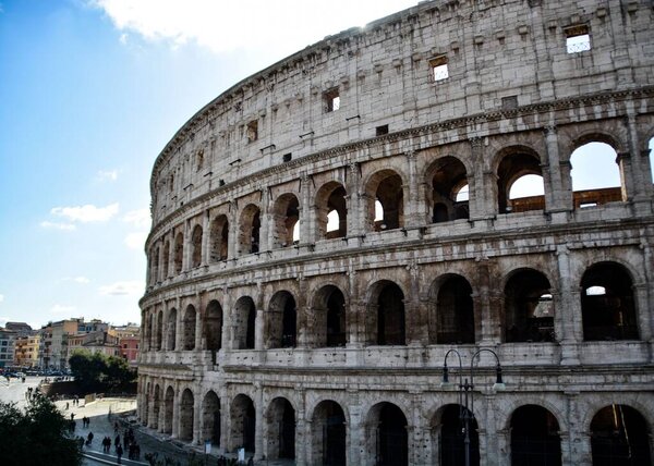 A side shot of the Colosseum in Rome, Italy under blue sky
