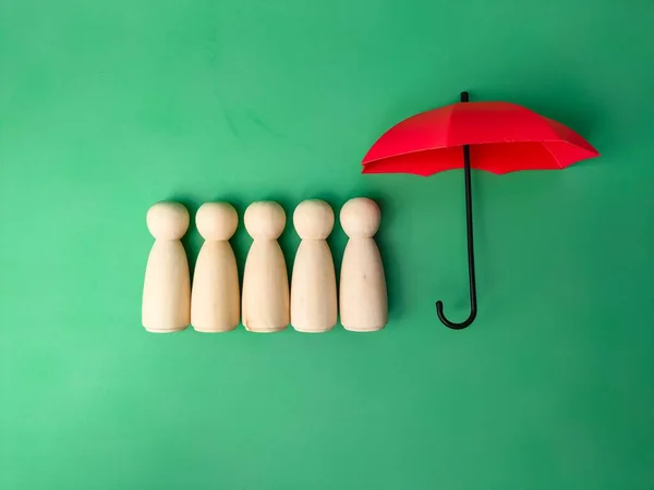 A red umbrella with peg dolls isolated on a green background