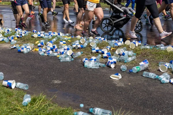 ライフ ワールド ランのための翼の間に地面に投げられたプラスチックボトルと紙コップ — ストック写真