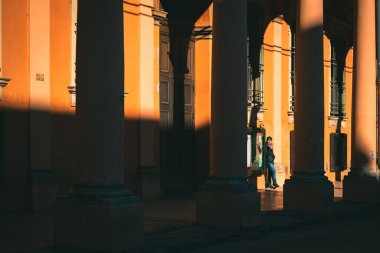 İtalya 'nın Bologna kentindeki tarihi yapı sütunları tarafından karanlık gölgeli bir duvara yaslanmış bir insan.