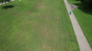 Yürüyen bir yolda koşan bir adamla çayır parkının havadan çekilmiş bir fotoğrafı.