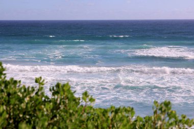 Kıyıya yakın bir su kütlesinin manzarası. Küçük dalgalar ve parlak güneş ışığı.