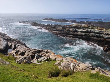 Kayalık sahile vuran deniz dalgalarının nefes kesici görüntüsü.