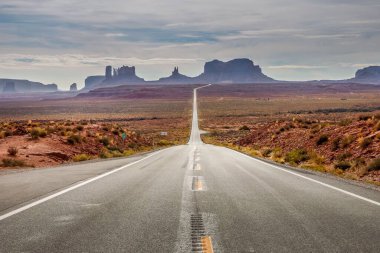 Utah-Arizona, ABD 'deki Monument Valley' de fırtınalı bir gökyüzünün altında düz bir yol.