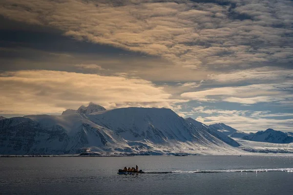 用Small Zodiac Motoring在Arctic中的应用研究了Small Zodiac Motoring Front Snow Covered Mountain Range — 图库照片