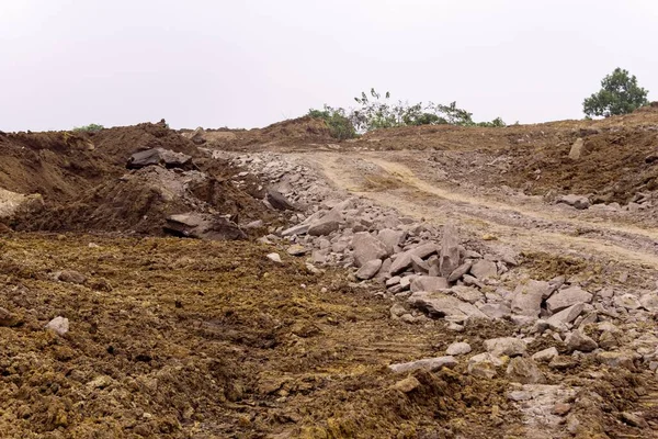 Kasvetli bir günde, kayalarla ve kuru otlarla kaplı bir tarla.