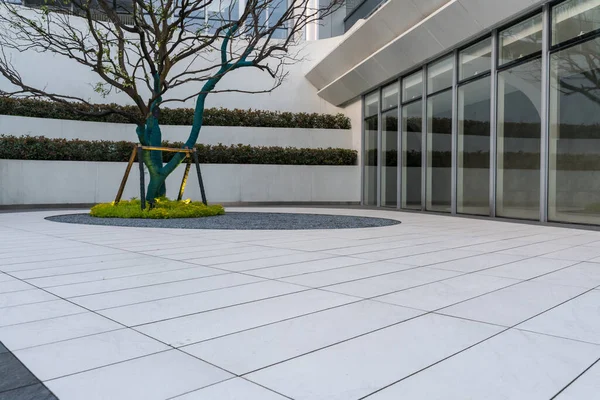 Modern ofis binasının önündeki beyaz ve gri zemin katın üst görüntüsü.