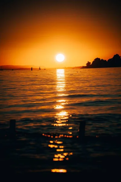 夏の夜の波打つ海の表面に反射する美しい輝く黄金のオレンジ色の夕日 — ストック写真