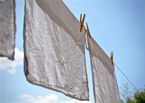 A closeup of a white laundry hang outside on a rope
