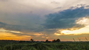 Gün batımında Almanya 'da bir çimen tarlasından geçen bulutların hızlandırılması