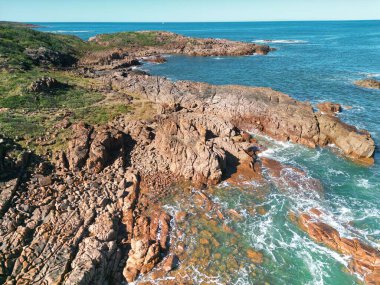 Port Stephens, Avustralya 'da ufukta mavi bir gökyüzü olan güzel kayalık bir sahil.