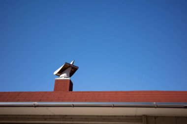 Açık mavi gökyüzüne karşı bacası olan kırmızı çatı