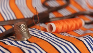 Turuncu ve beyaz çizgili kumaş üzerinde turuncu iplik ve yüksük makarası