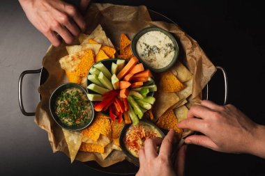 Bir kase meze ve doğranmış sebze cipsi ve çorbayla el ele tutuşmak.