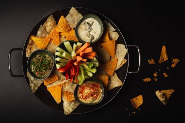 Aperatif kasesinin en iyi pozu. Siyah bir masada doğranmış sebze cipsi ve çorba.