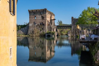 Visconti Köprüsü 'nün kalıntıları İtalya' nın Veneto bölgesinde Valleggio sul Mincio 'nun bir köyü olan Borghetto Konsolosu Mincio' nun sularına yansıyor.